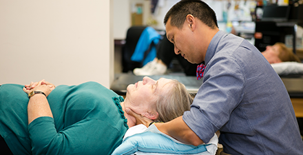 A male PT works on an older woman's neck