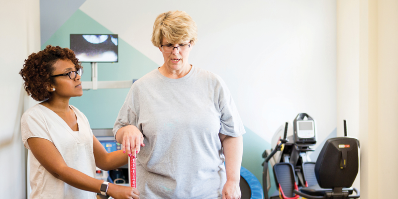 Female PT helping a patient stand