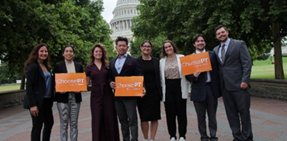 Group of eight advocates holding orange ‘ChoosePT’ signs outdoors, with trees and the U.S. Capitol building visible in the background.