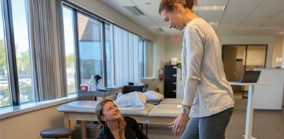 A female PT works with a patient in a clinic