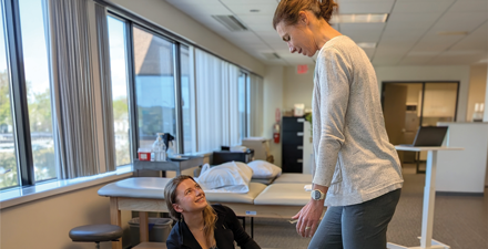 A female PT works with a patient in a clinic