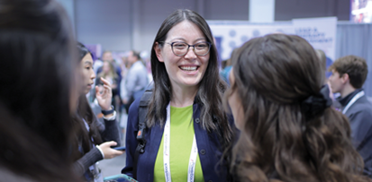 A conference attendee speaks to two others