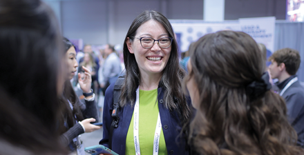 A conference attendee speaks to two others