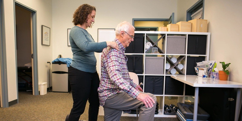 A PT works on an older man's upper back