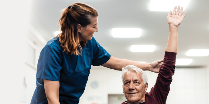 A PT stretching an older man's left arm